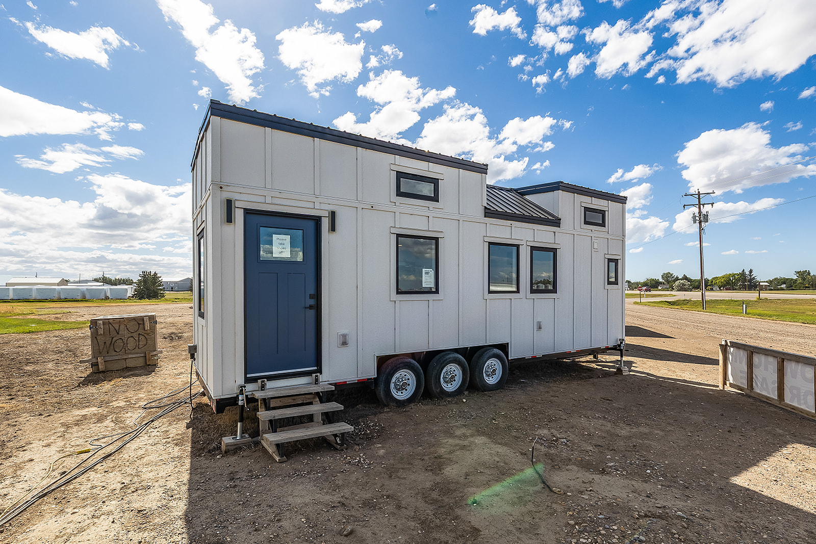 A tiny home exterior with white siding, black accents and a blue door