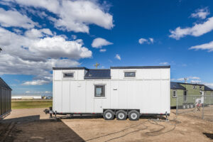 A tiny home exterior with white siding and black accents