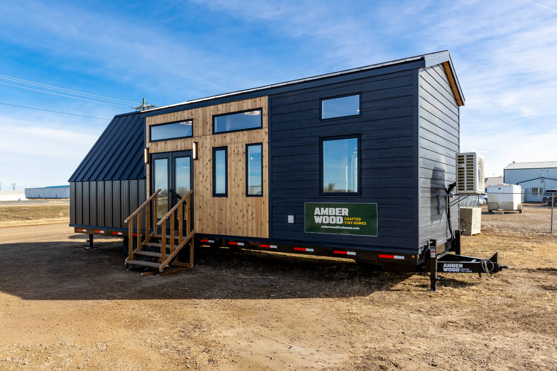 Black tiny home exterior with wood accents, black trim windows and patio doors
