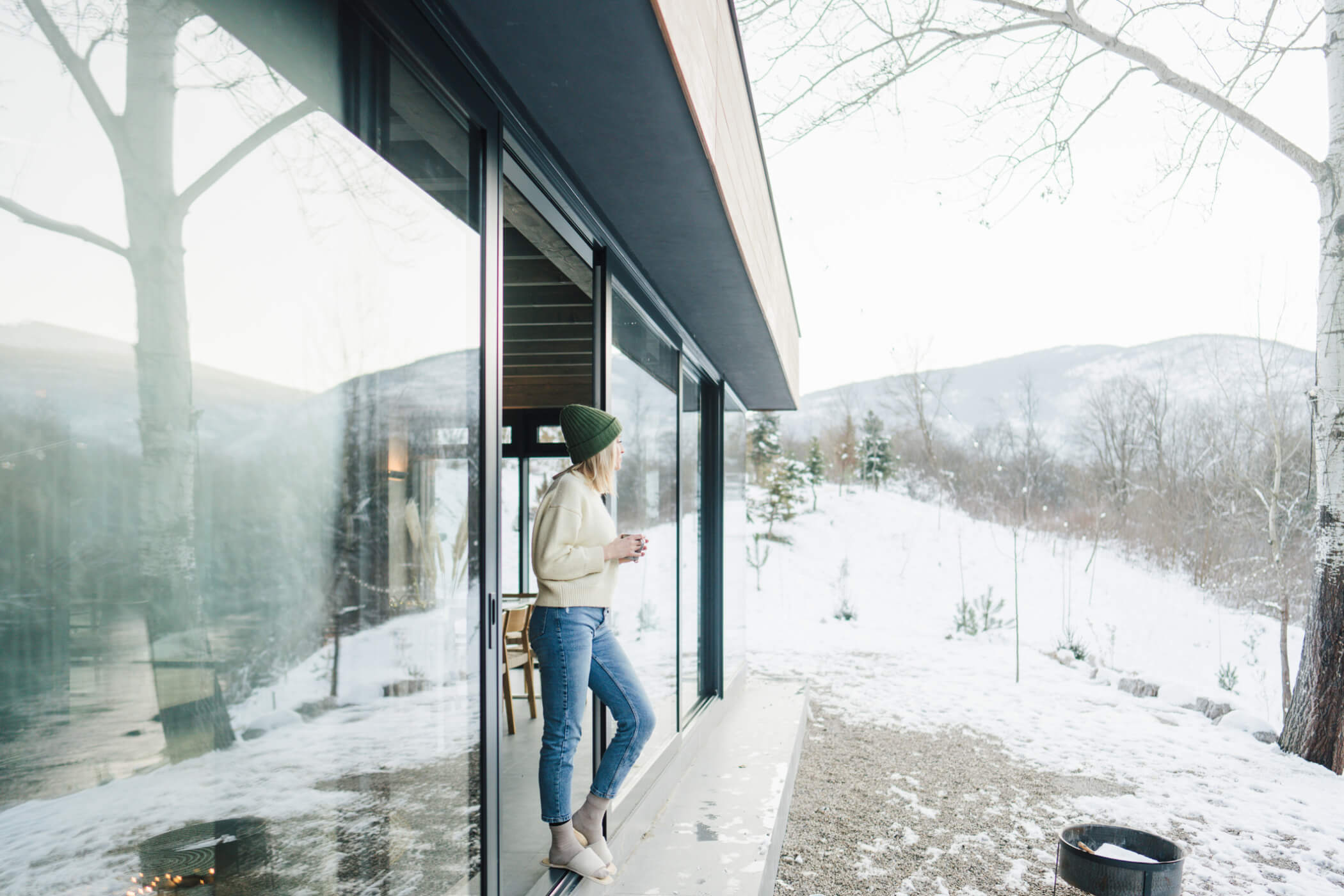 Woman enjoying winter view outside a modern custom tiny home built for four-season living