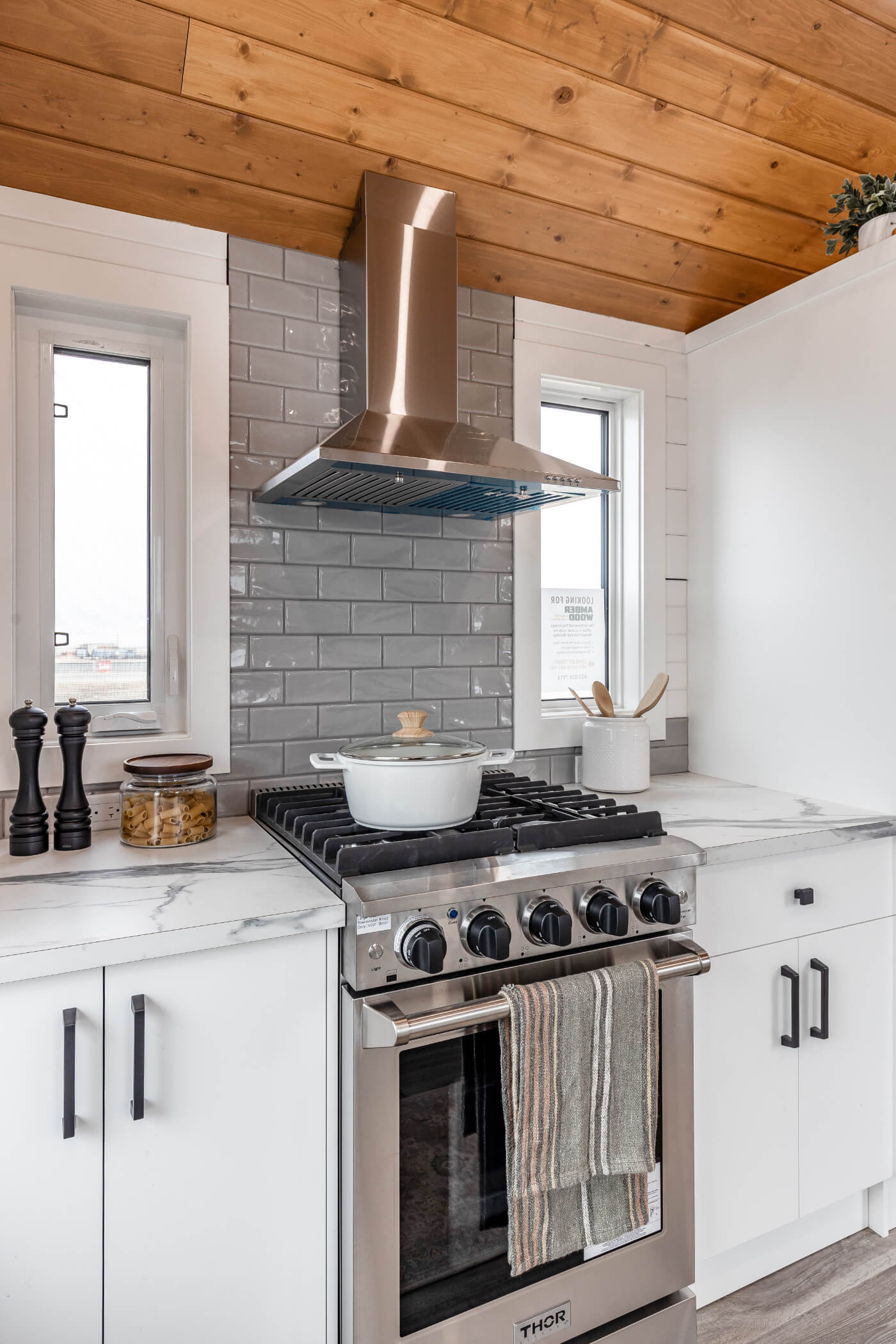 Tiny home kitchen with white cabinets, bright windows and modern hardware