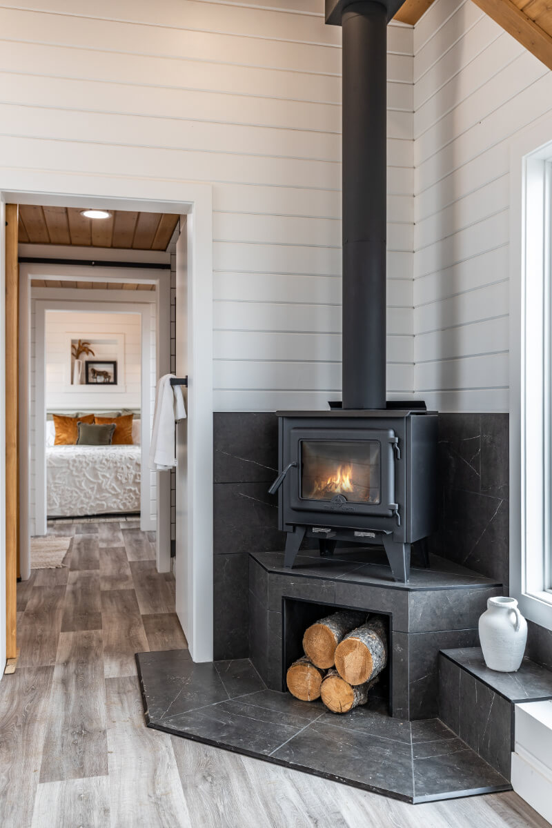 A cozy wood fire stove in a tiny home, with chopped wood