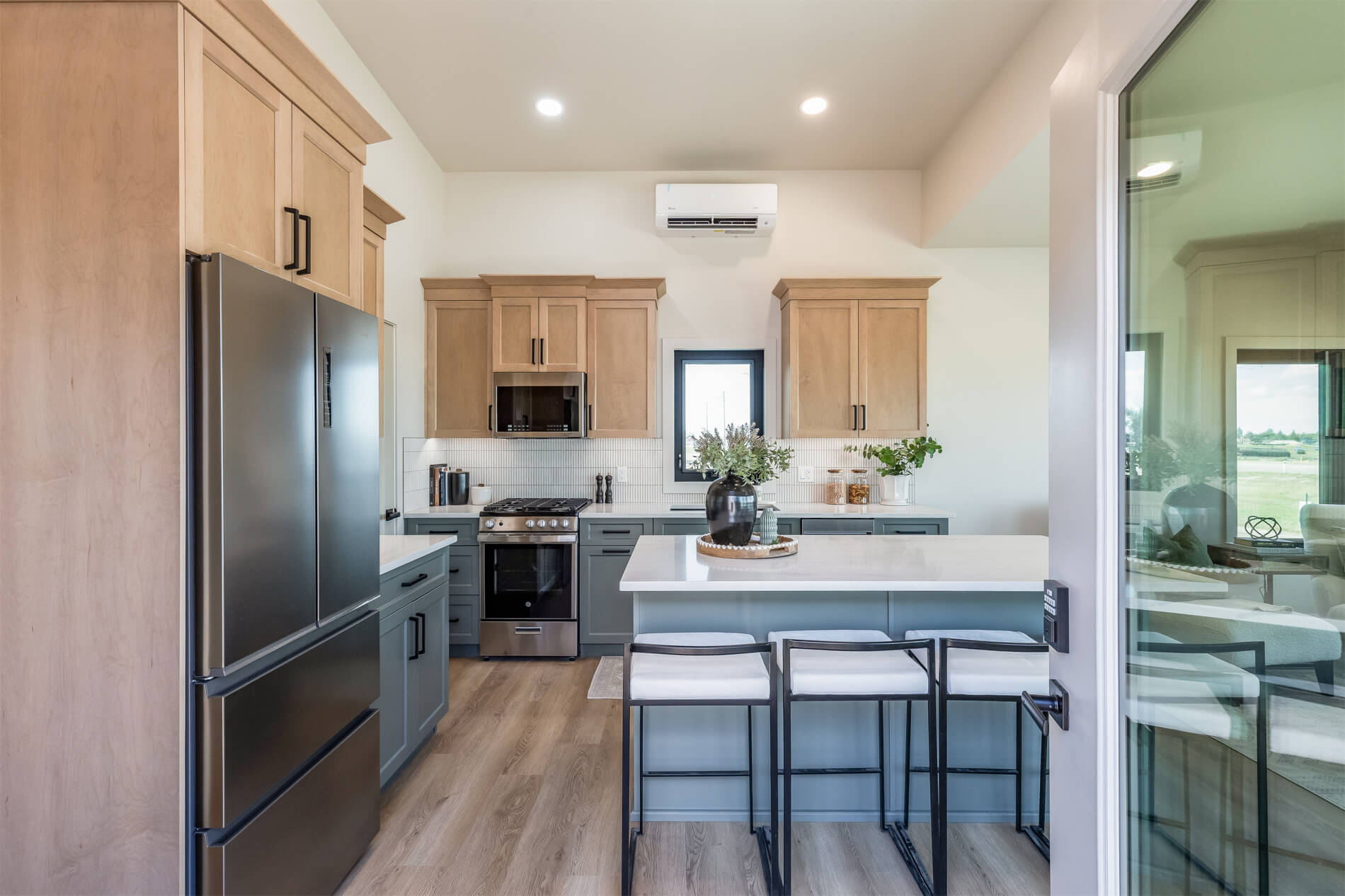 Tiny home open kitchen with light wood and blue cabinets, white countertops and an island