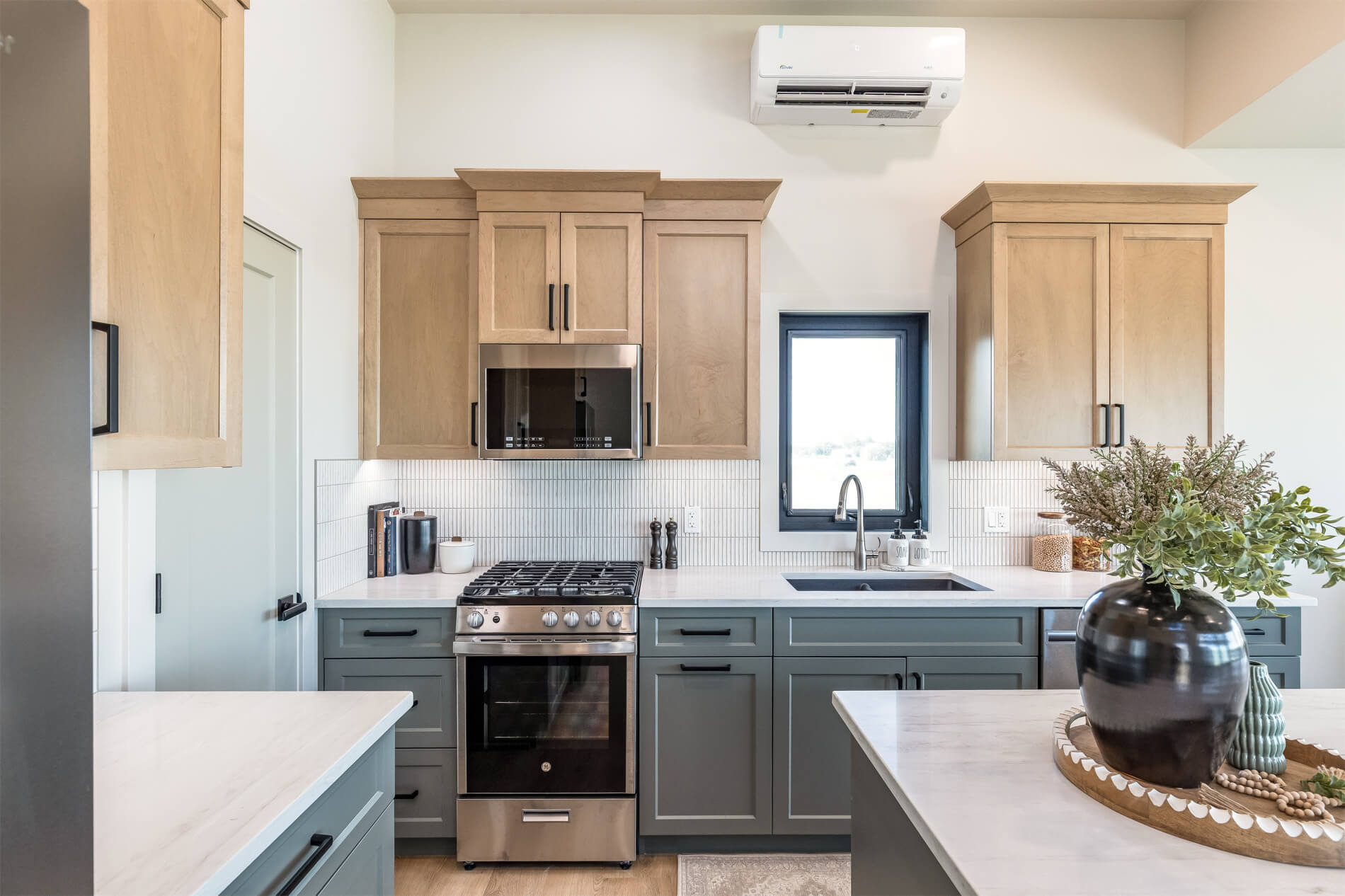 Tiny home open kitchen with light wood and blue cabinets, white countertops and an island