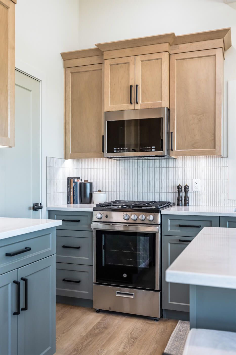 Tiny home open kitchen with light wood and blue cabinets, white countertops and an island