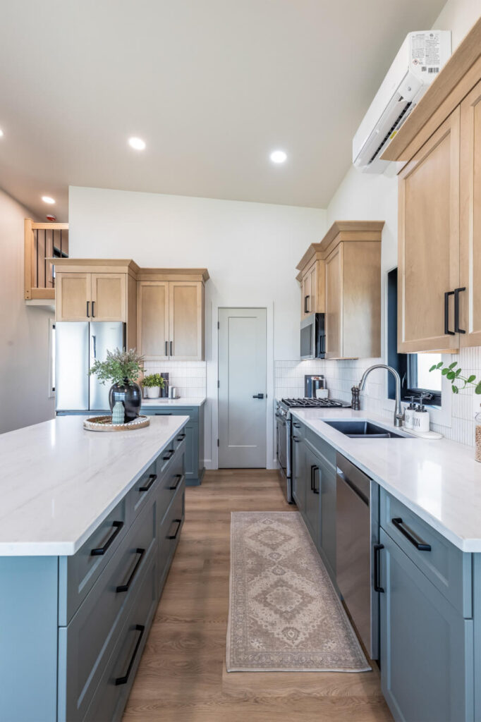 Tiny home open kitchen with light wood and blue cabinets, white countertops and an island