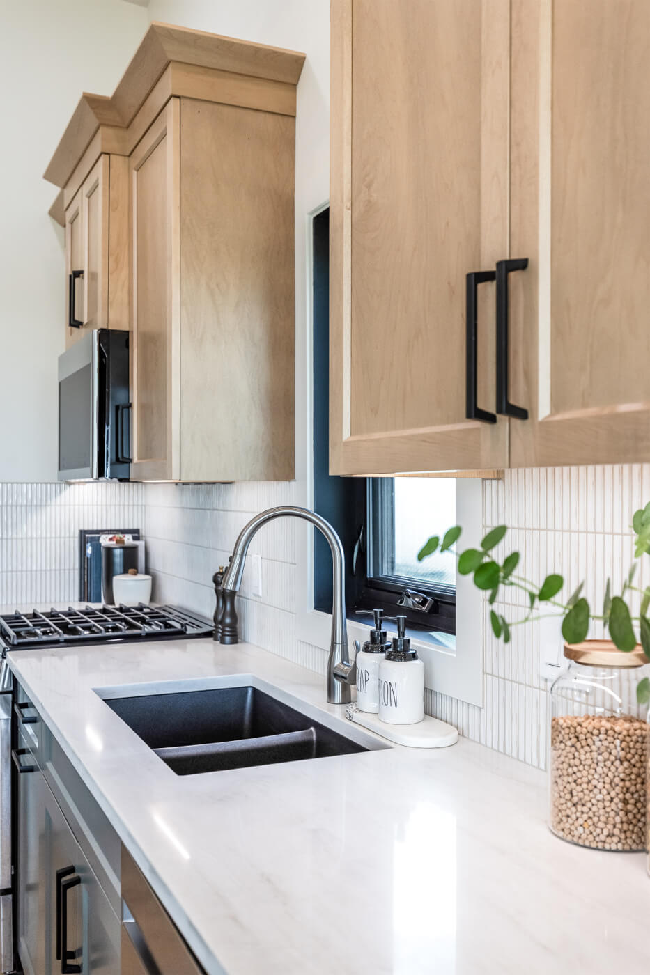 Tiny home kitchen sink with white countertops and light wood cabinets