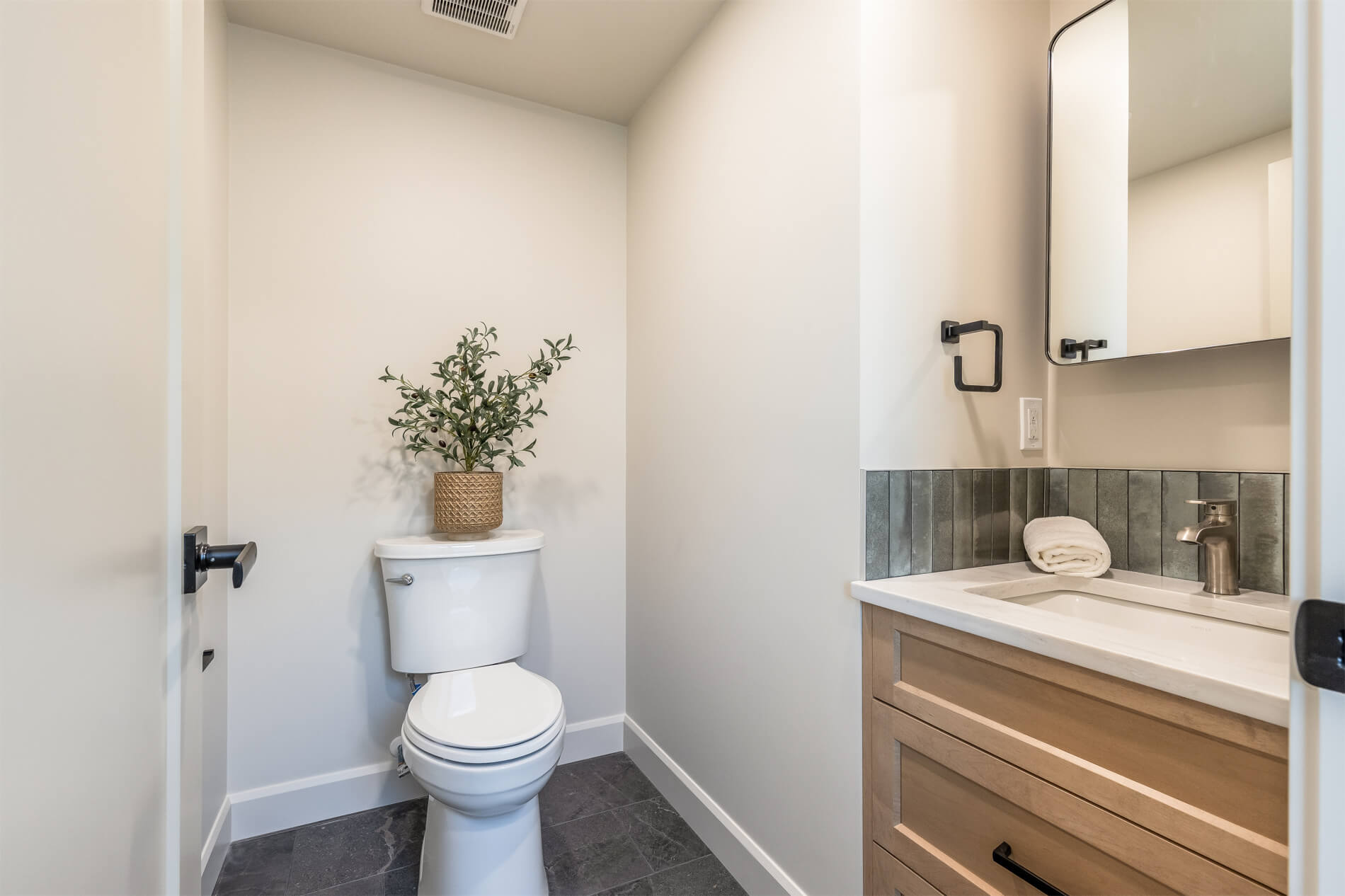 A tiny home half-bath with white walls and a light wood vanity