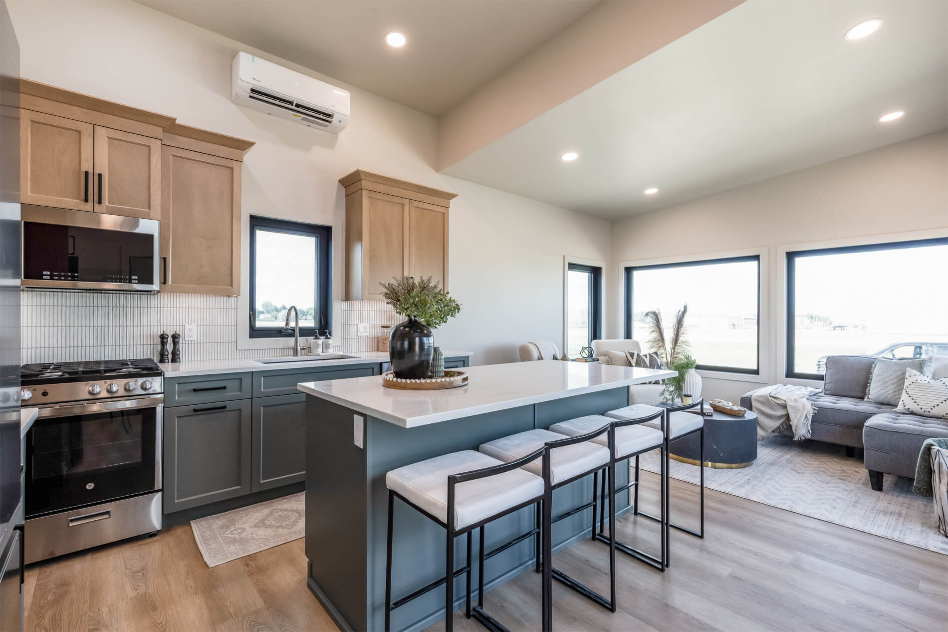 Tiny home open kitchen with light wood and blue cabinets, white countertops and an island