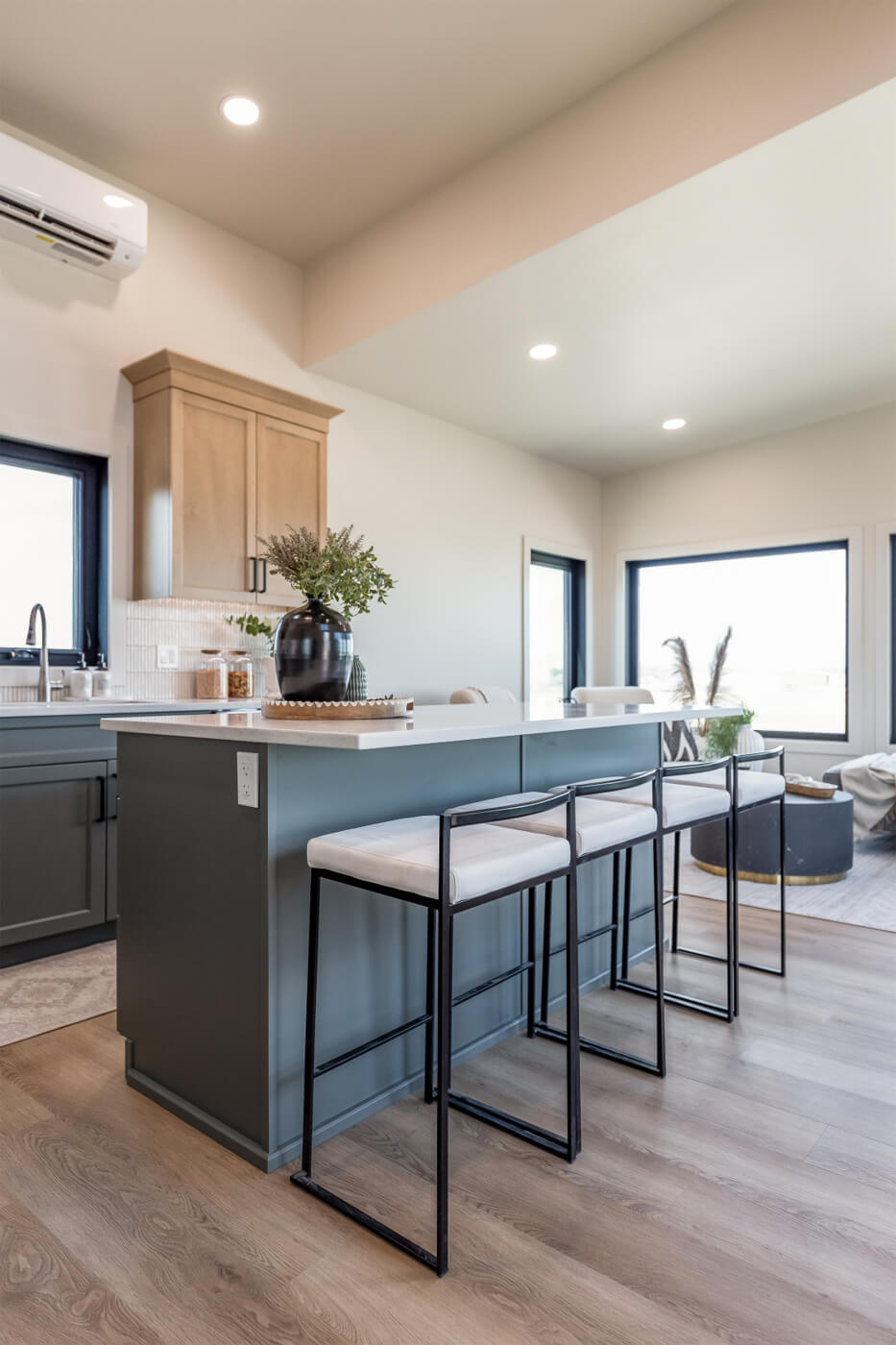 Tiny home open kitchen with light wood and blue cabinets, white countertops and an island