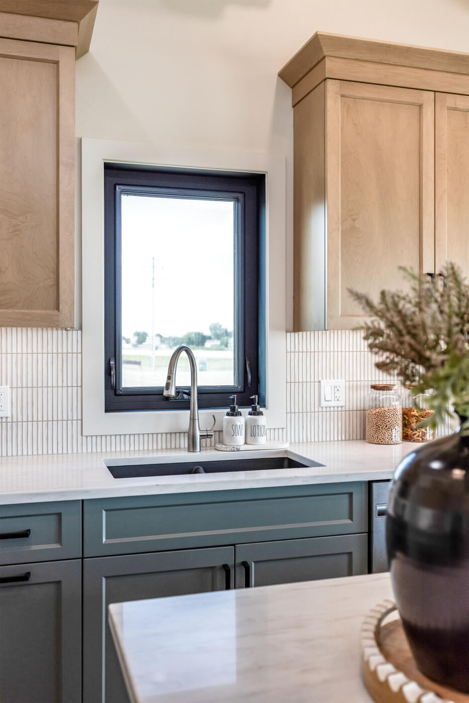 Tiny home kitchen sink with white countertops and light wood cabinets