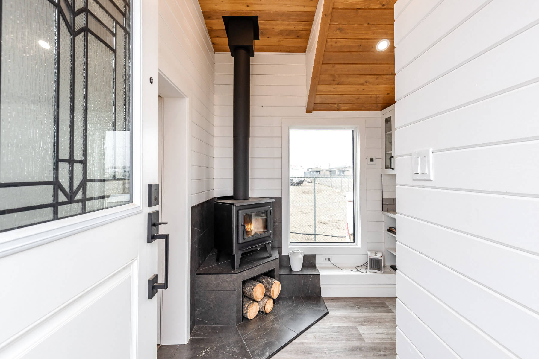 A cozy wood fire stove in a tiny home, with chopped wood