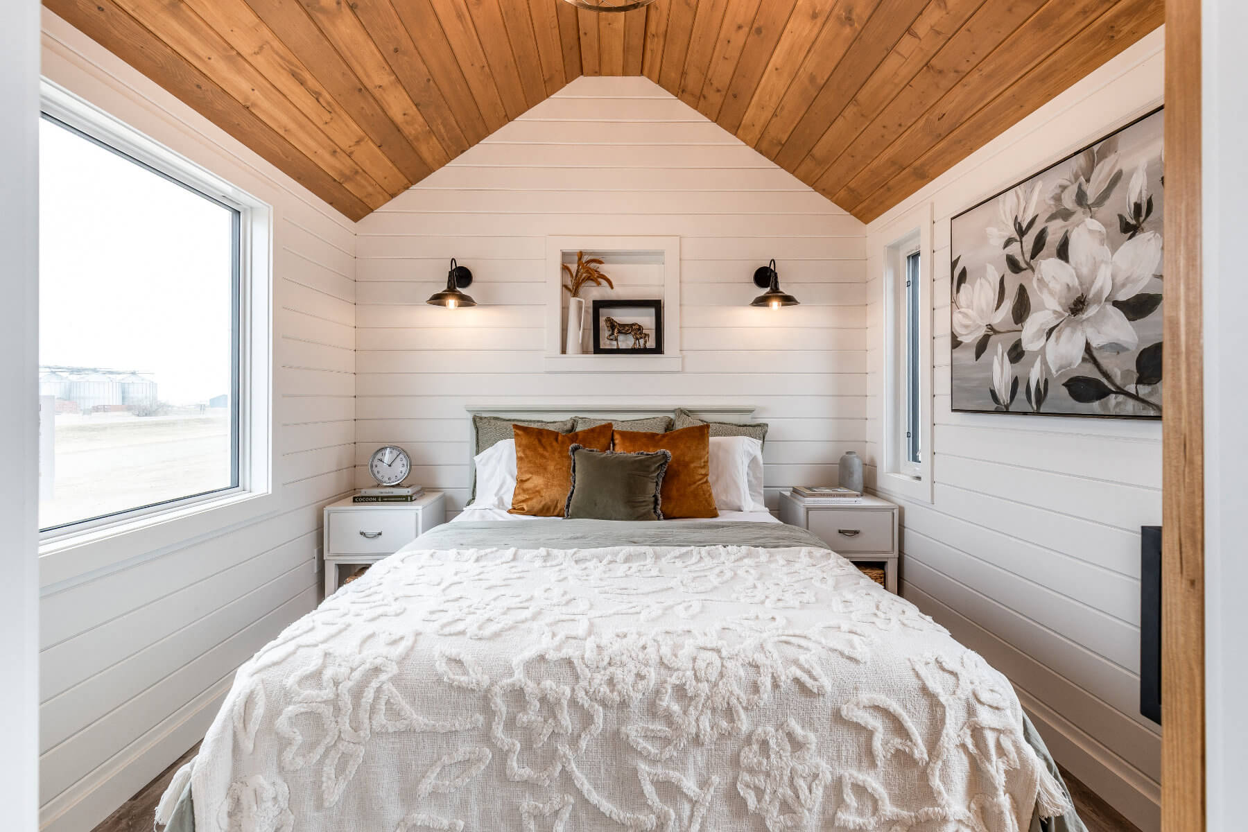 Cozy tiny home bedroom with stylish bedding and bright windows