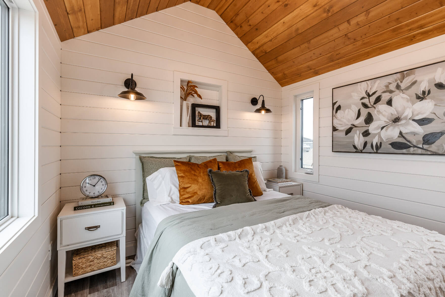 Cozy tiny home bedroom with stylish bedding and bright windows