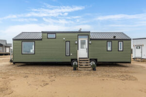 Tiny home exterior with green siding, black trim windows and a black roof
