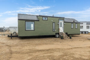 Tiny home exterior with green siding, black trim windows and a black roof