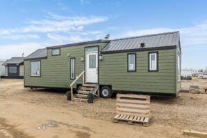 Tiny home exterior with green siding, black trim windows and a black roof
