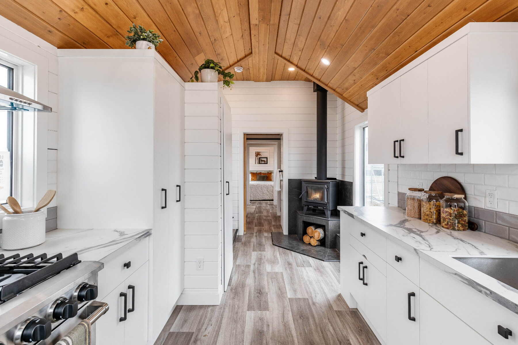 A tiny home interior with a cozy wood stove and clean white cabinets for storage